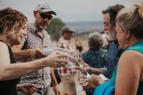 People pouring and tasting wine outdoors.
