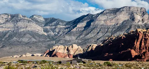 A landscape photograph showing rugged mountains and red rock formations.