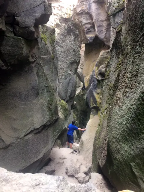 A person explores a narrow rock canyon.