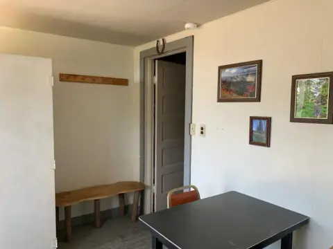An interior view of a room with a rustic wooden bench, a table, and pictures on the wall.