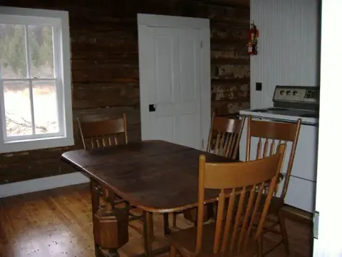 A rustic wooden cabin interior with a dining table and chairs.