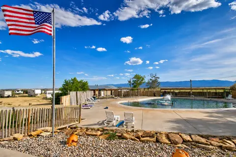 An outdoor swimming pool and lounge area with an American flag under a blue sky.