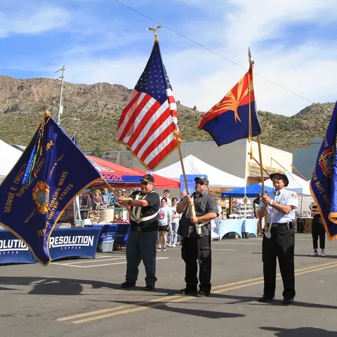 Three people holding flags outdoors during an event.