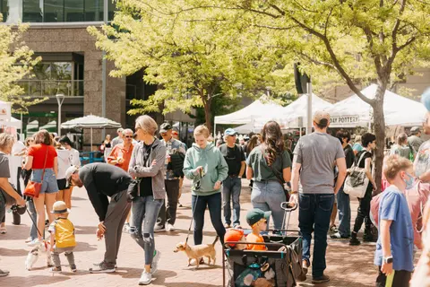 A crowd of people walking through an outdoor market or fair.
