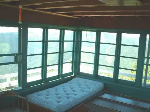 Interior of a room with many windows and a mattress.