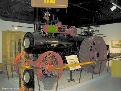 An antique steam tractor on display indoors.
