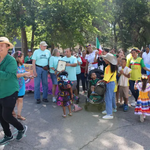 A group of people gathered outdoors during an event, with one person holding a certificate.