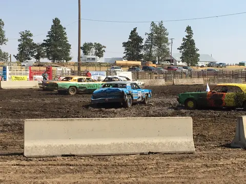 Demolition derby cars in a muddy arena.