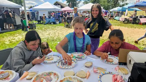 Children decorating cookies at an outdoor market event.