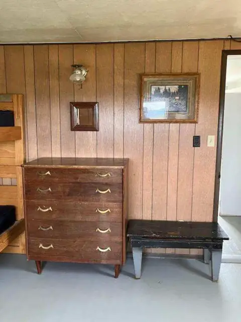 An interior room features wood paneling, a wooden dresser, and a bench.