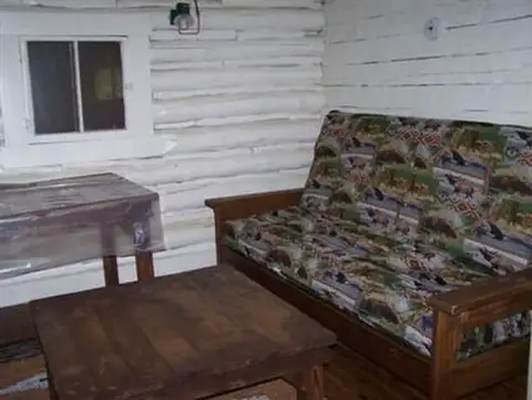 Interior view of a rustic log cabin room with a couch and table.