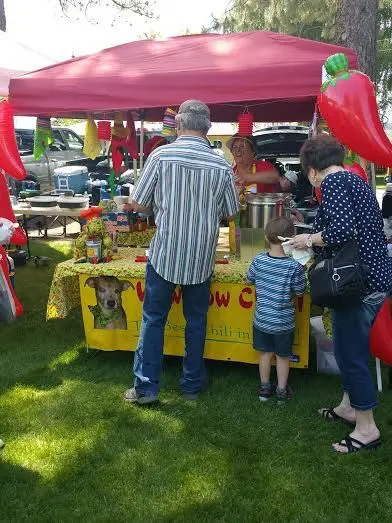 People at a food booth under a red canopy.