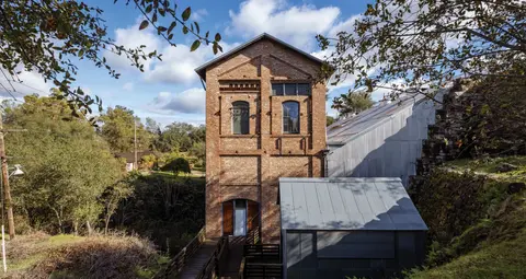 Exterior view of a multi-story brick industrial building surrounded by trees and a blue sky.