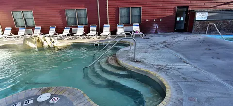 A hot spring pool with lounge chairs lined up against a red building.
