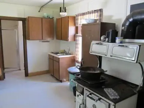 An interior view of a historic kitchen with wooden cabinets and a vintage stove.