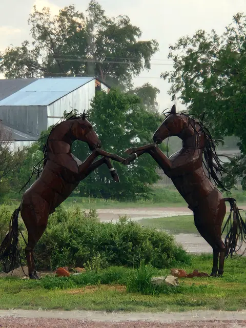 Two metal horse sculptures rearing up facing each other outdoors.