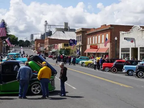 A street lined with classic cars and people attending a car show.
