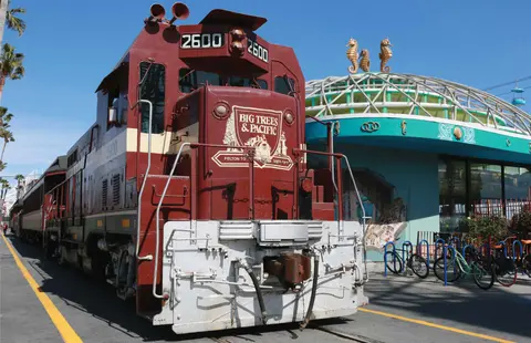 A brown and white locomotive parked outside a building.