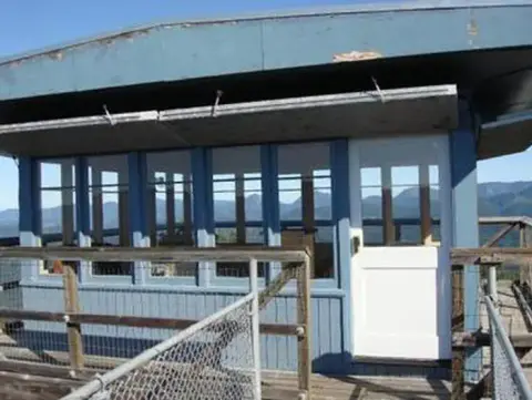 A fire lookout tower cabin with windows and a white door.