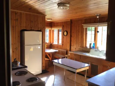 A rustic kitchen interior with wood paneling on walls and ceiling.