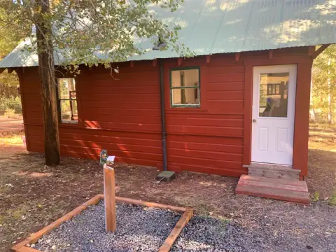 Exterior view of a small red cabin with a green metal roof.