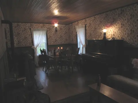 An interior view of a room with a dining table and a piano.