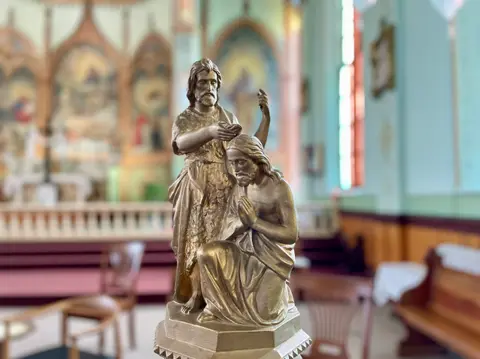 A statue depicting the baptism of Jesus inside a church.