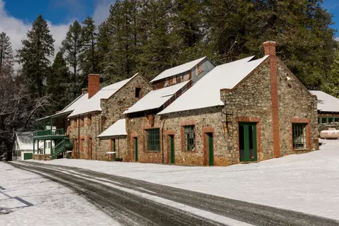 Exterior view of a historic stone building with snow on the roof and ground.