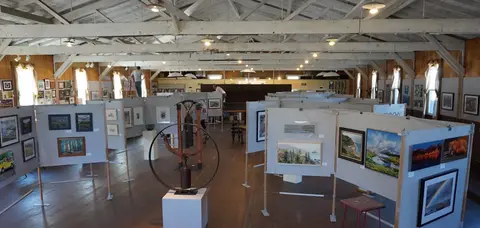 An art exhibition displayed inside a large wooden hall.
