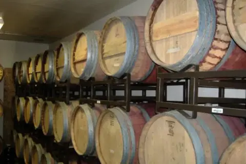 Rows of wooden wine barrels stacked in a cellar.