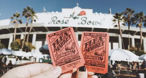 Two admission tickets held in front of a stadium.