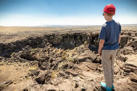 A young boy looks out over a rocky landscape.