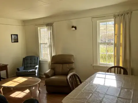 A furnished room with seating, a table, and windows.