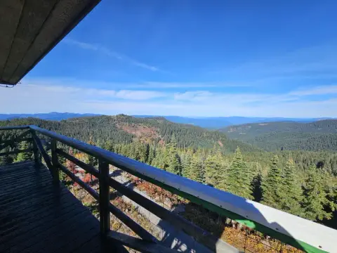 A view of a vast forested mountain landscape from a wooden balcony.