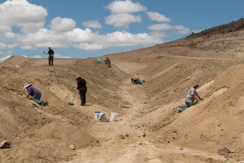 People excavating in a dry, hilly landscape.