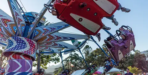 People ride an amusement park ride outdoors.