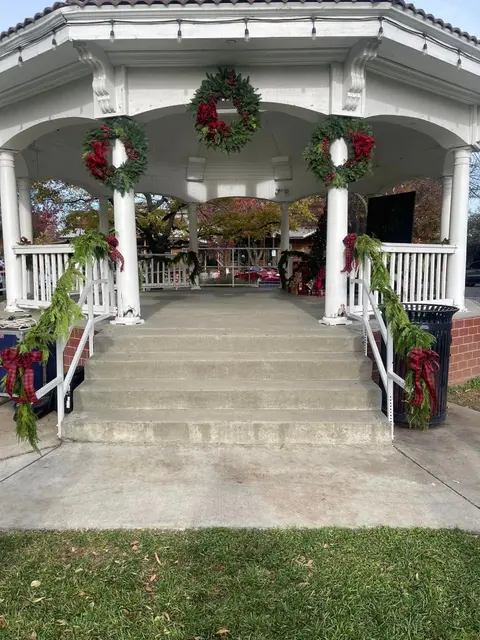 A white gazebo decorated with holiday wreaths and garlands.