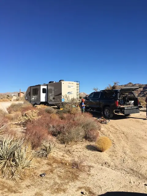 A camper trailer and a pickup truck parked in a desert landscape.