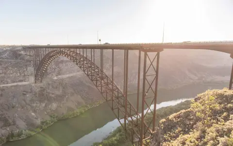 A large steel arch bridge spans over a river and canyon.