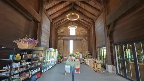 An interior view of a wooden barn-style building with high ceilings and displays.