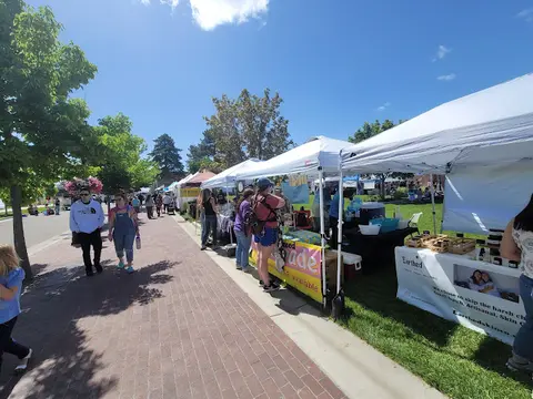 An outdoor market with white tents set up along a brick walkway.