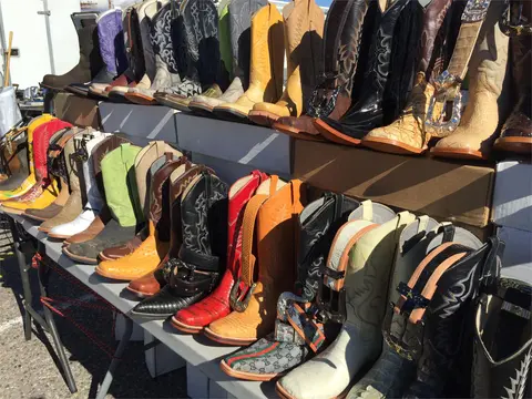 A colorful display of many cowboy boots arranged on tables.
