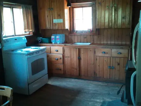 A rustic wooden kitchen interior with a white stove and cabinets.