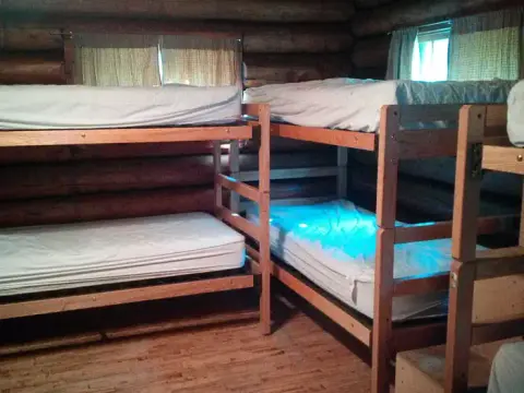 Wooden bunk beds inside a rustic log cabin.