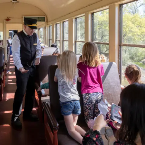 A conductor interacts with children inside a train car.