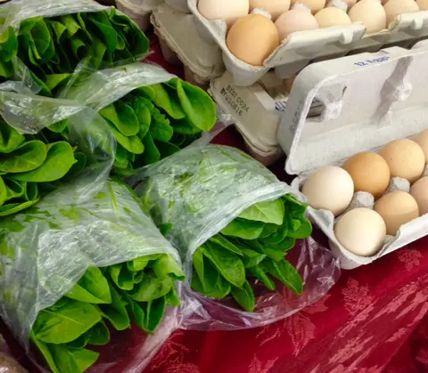 Fresh greens and cartons of eggs on a red table.
