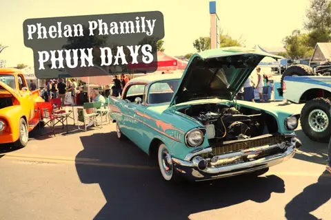 A classic turquoise car with its hood open parked at an outdoor event.