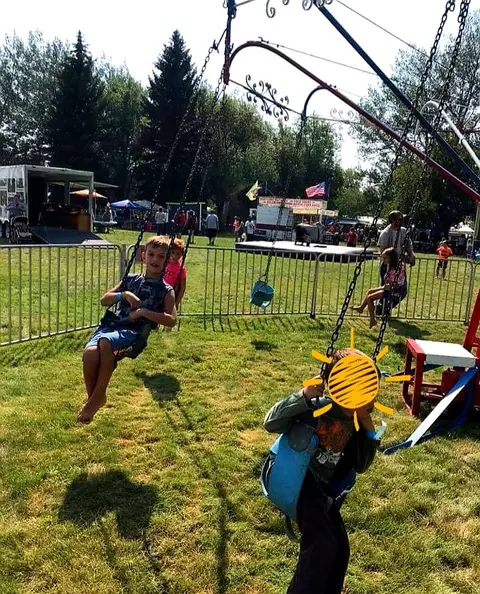 Children riding a swing ride at an outdoor event.