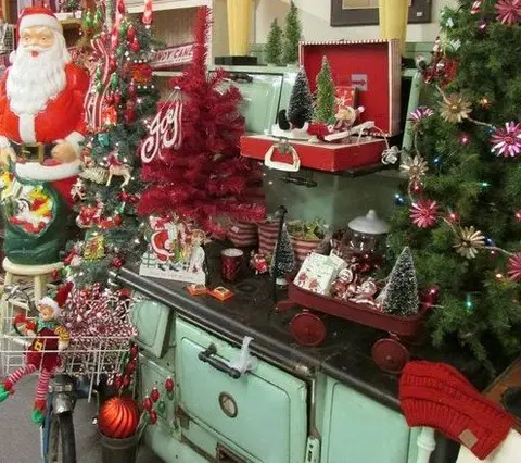 A vintage stove decorated with Christmas items and trees.