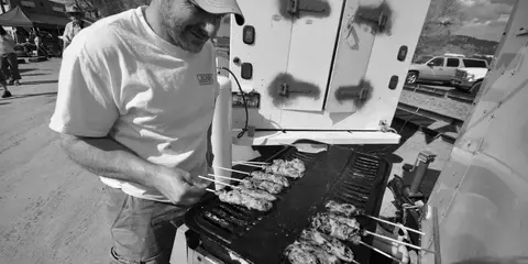 A man grills food on skewers outdoors.